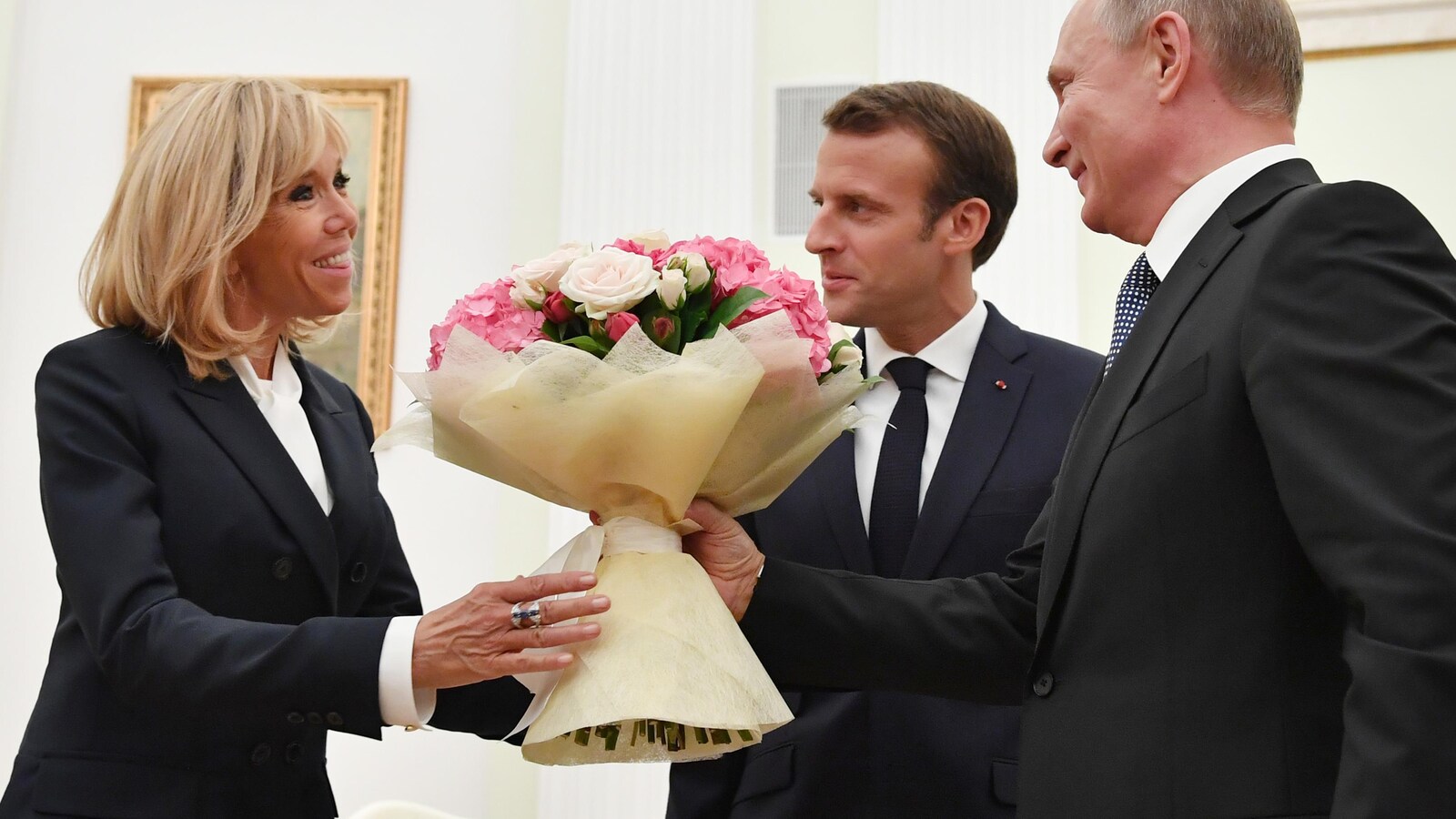 Le président russe Vladimir Poutine offrant un bouquet de fleur à Brigitte Macron avant la rencontre avec son homologie français, Emmanuel Macron, au Kremlin.