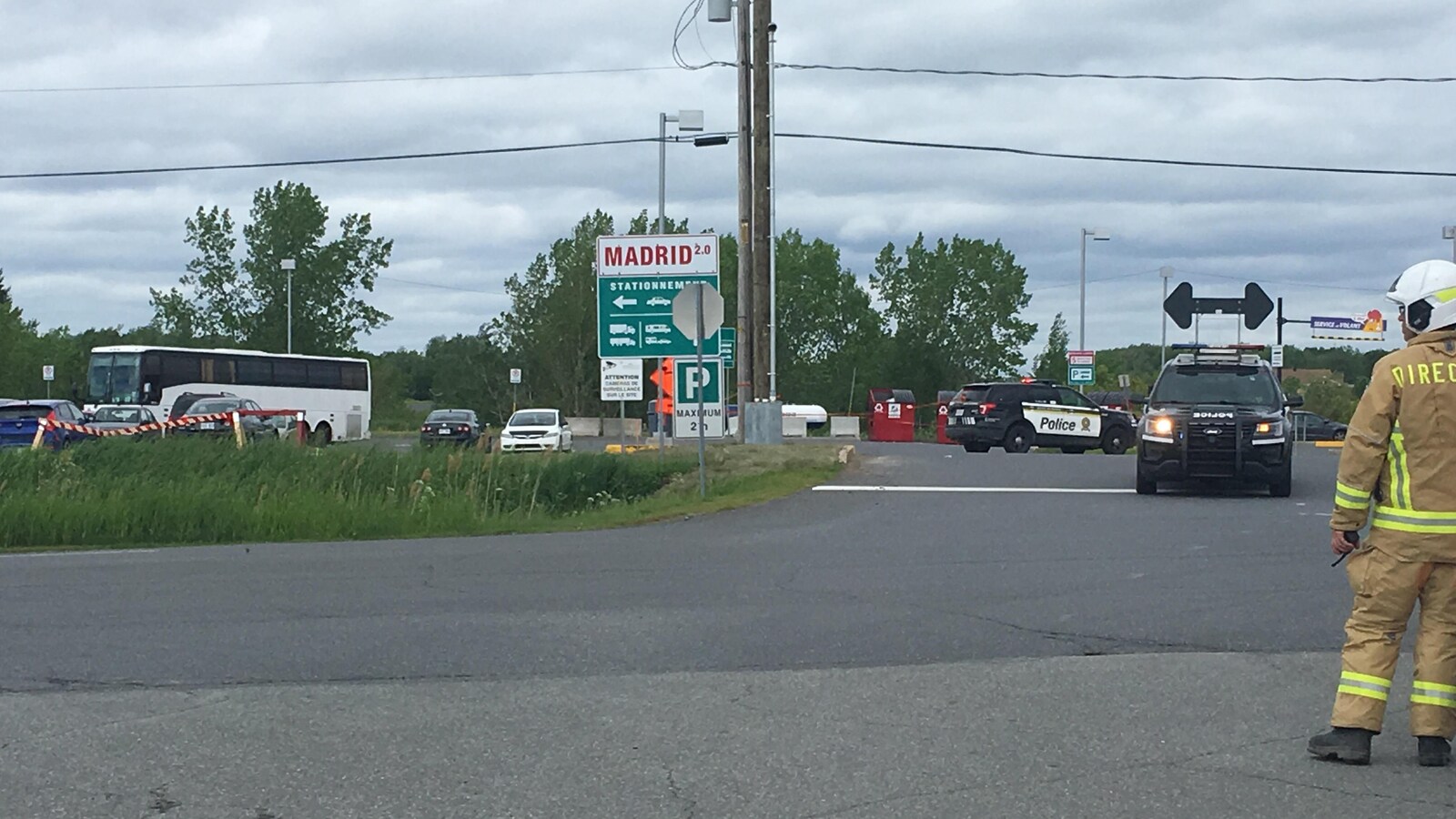 Pompier, véhicules de la Sûreté du Québec et autobus dans le stationnement.