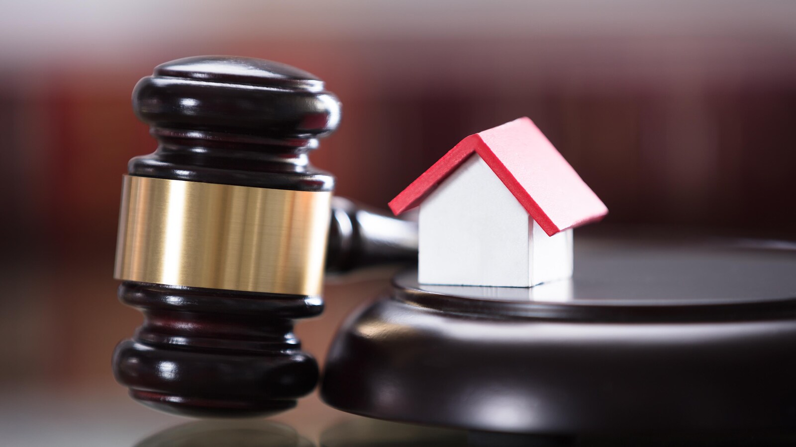 Une maillet de juge et une maison miniature dans une cour de justice.