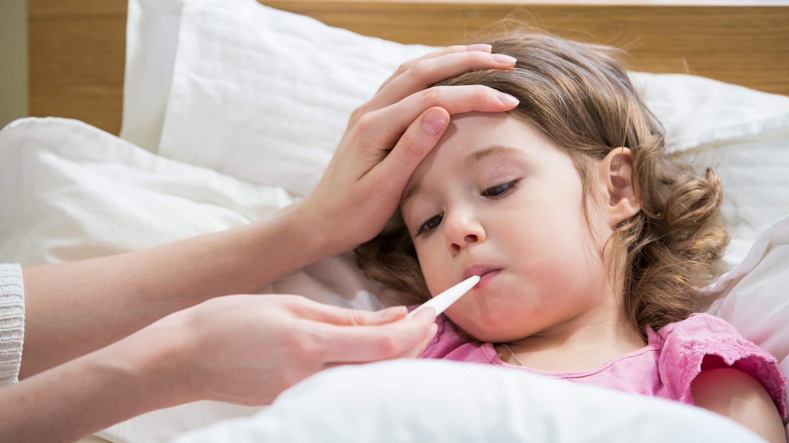 Une mère prend la température de son fille malade.