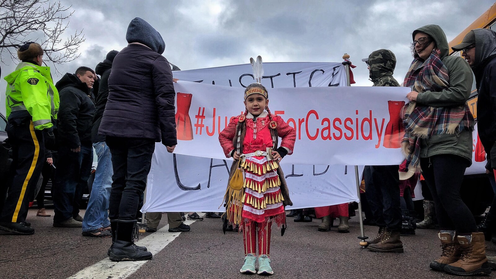 Fillette en vêtements traditionnels micmacs devant une bannière « Justice pour Cassidy » le 21 novembre 2018 à Canso, en Nouvelle-Écosse.