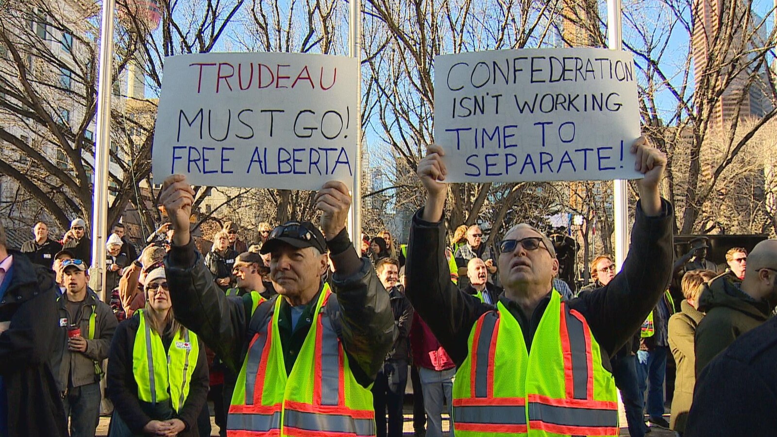 Deux manifestants à un ralliement en faveur de l'énergie pétrolière portent des pancartes en faveur de l'indépendance de l'Alberta.