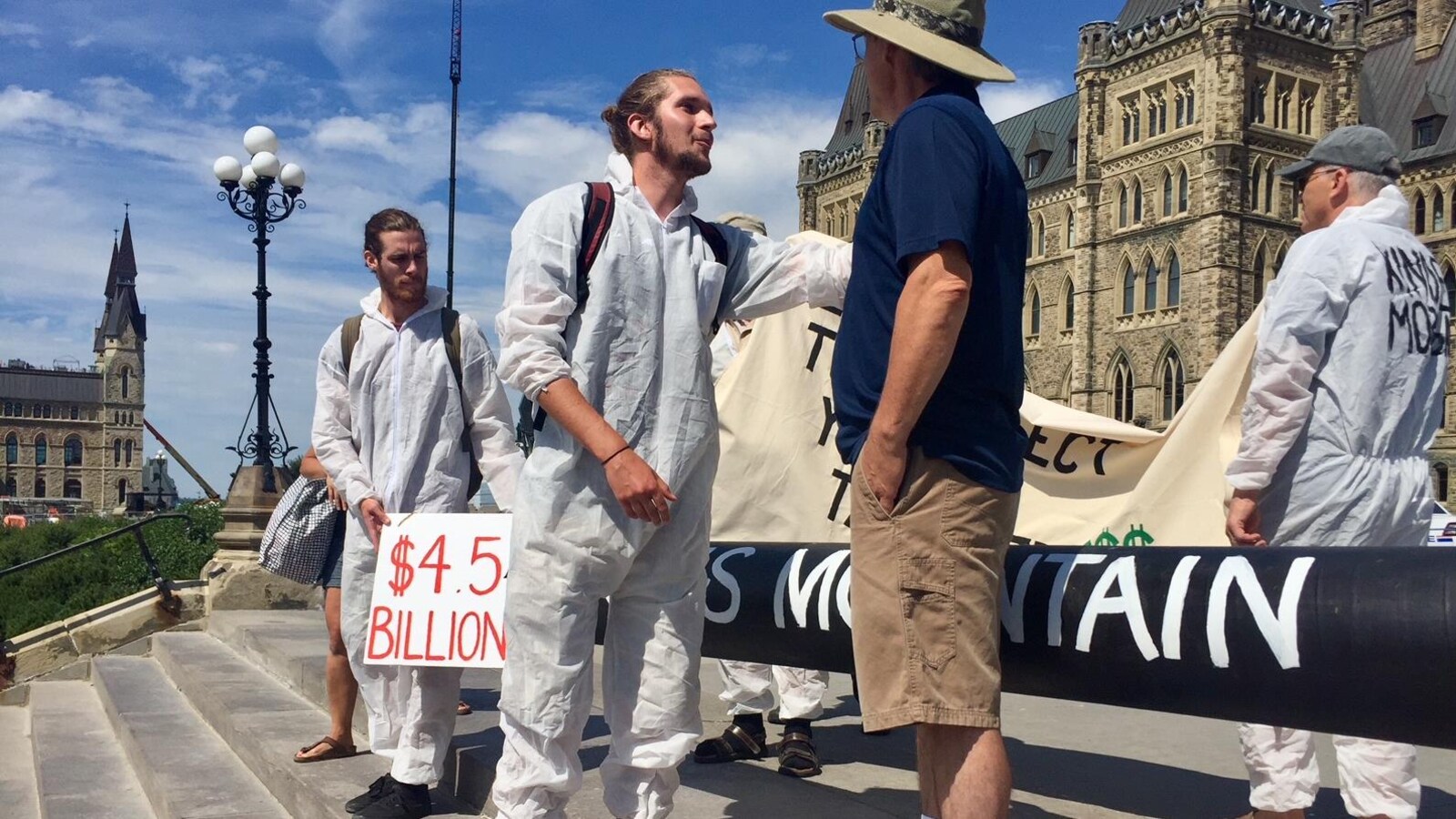 Un manifestant en combinaison blanche discute avec un visiteur de la colline du Parlement.