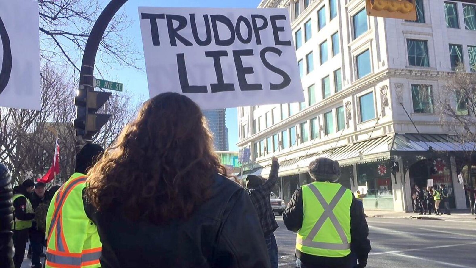 Des manifestants propipeline portant des gilets jaunes brandissent des pancartes devant l'hôtel de ville à Calgary.