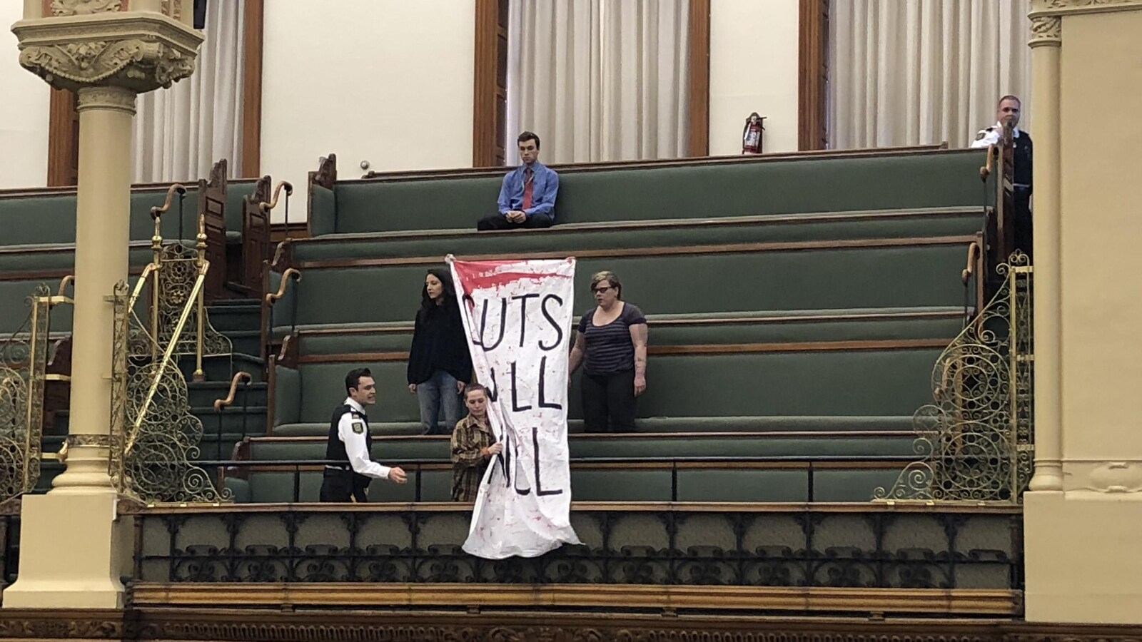 Des manifestants brandissent une banderole à l'intérieur de Queen's Park.