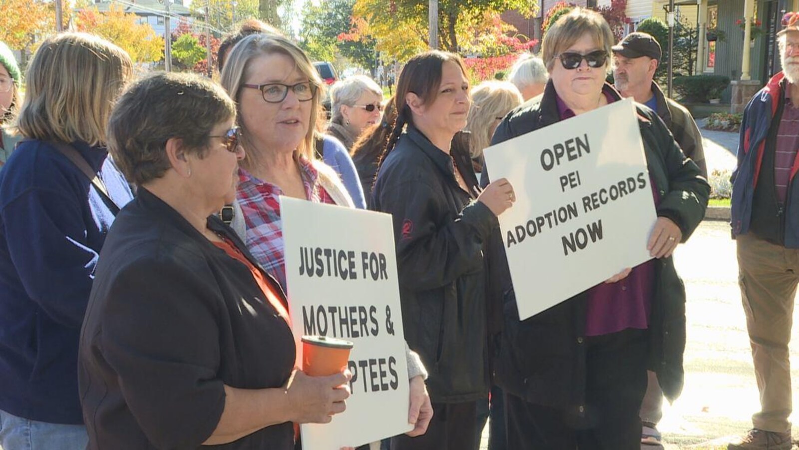 Des manifestants tiennent des pancartes et réclament «justice pour les mères et les personnes adoptées».