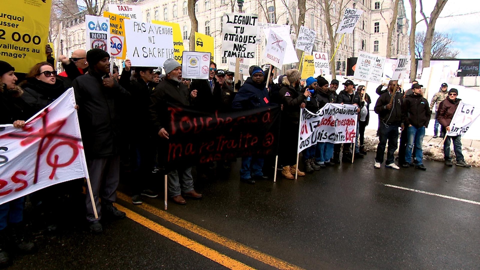 Des manifestants sont immobilisés sur la Grande Allée, devant l’hôtel du Parlement, à Québec. Plusieurs brandissent des affiches invitant le gouvernement Legault à renoncer à son projet de loi visant à déréglementer l’industrie du taxi.