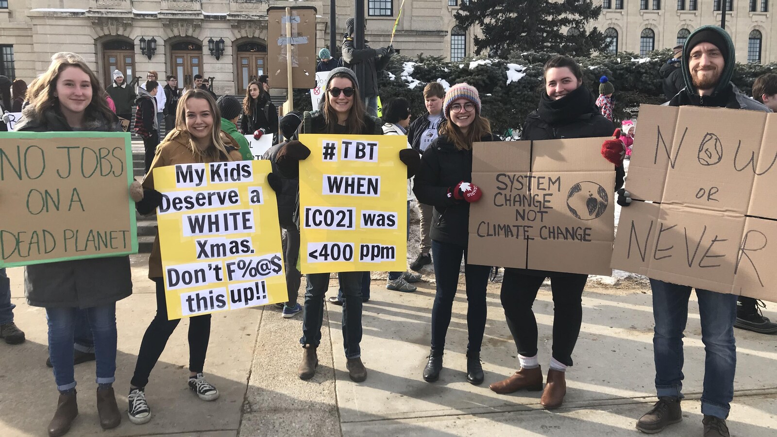 6 Réginois posent avec leur pancartes devant le palais législatif à Regina