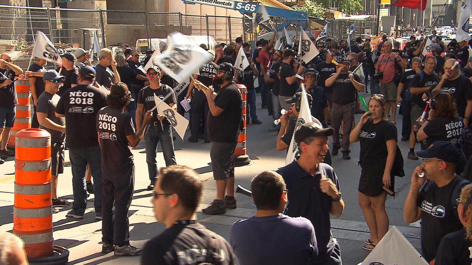 Des dizaines de syndiqués portant des t-shirts noirs manifestent dans la rue.