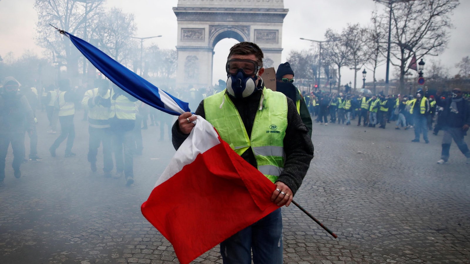 Un manifestant tient un drapeau français sur l'avenue des Champs-Élysées, lors d'une journée nationale de protestation du mouvement des « gilets jaunes » à Paris, le 8 décembre 2018.