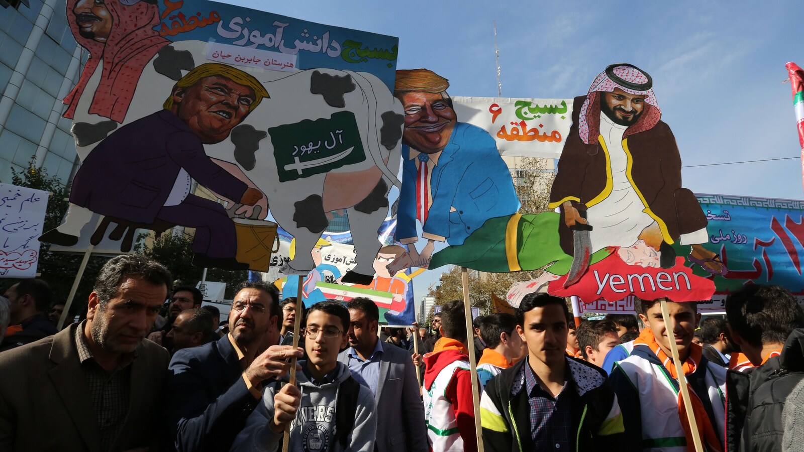Des manifestants brandissant des caricatures montrant le président américain Donald Trump en train de traire le lait d'une vache frappé d'un drapeau saoudien sur le côté et portant la tête du roi Salmane d'Arabie saoudite.