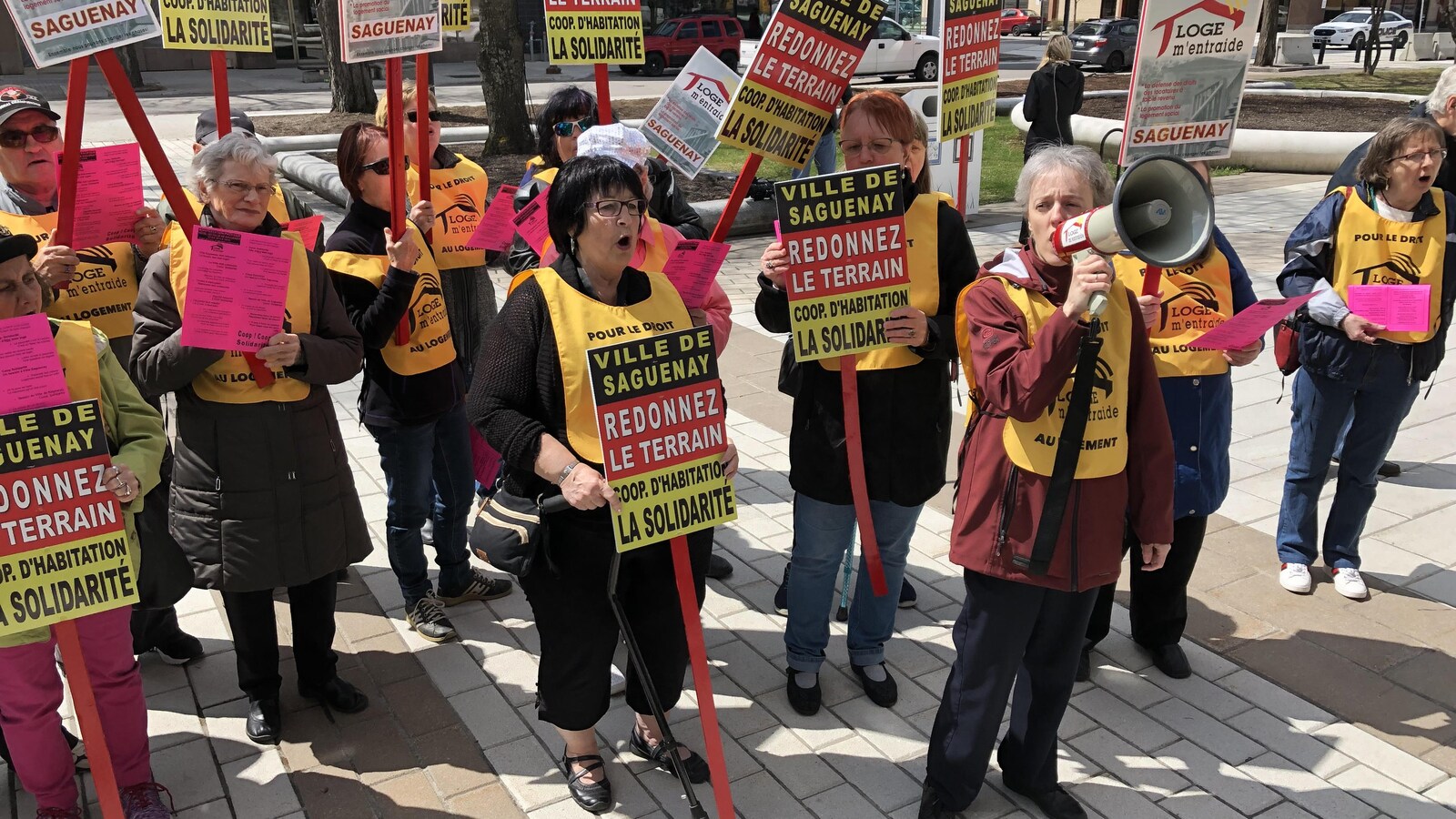 Des manifestants réunis à la Place du Citoyen et tenant des pancartes.