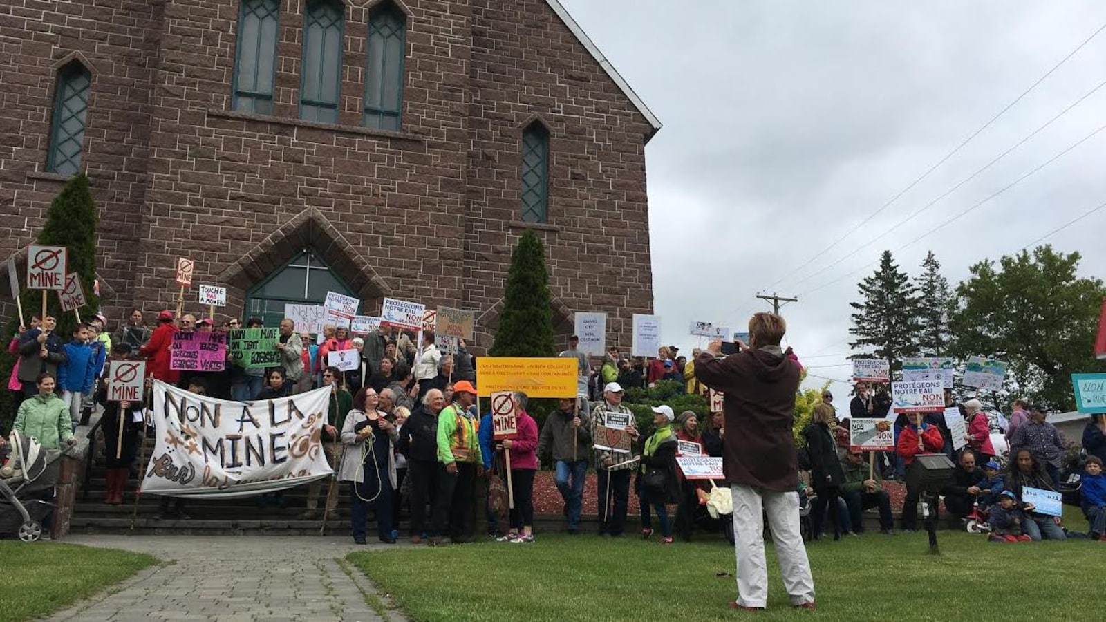 Des citoyens de Grenville-sur-la-Rouge se sont mobilisés, devant l'église, samedi après-midi contre le projet minier projeté dans leur municipalité. On y voit une affiche qui dit « non à la mine .»