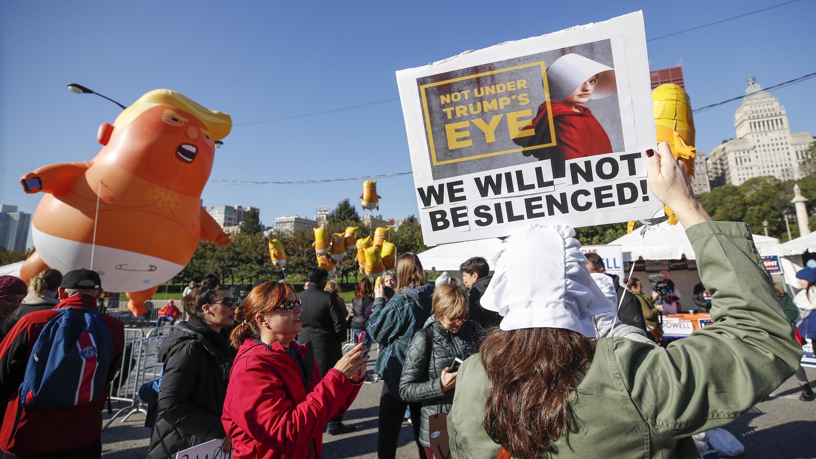 Un groupe de manifestants avec des pancartes et un ballon gonflable géant à l'effigie de Donald Trump marchent dans les rues de Chicago.