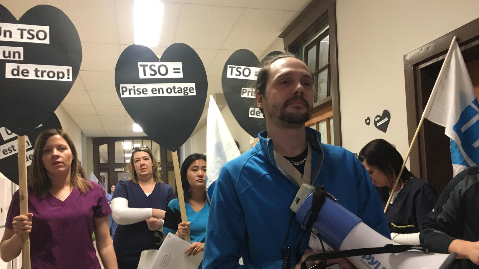 Plusieurs infirmiers et infirmières tiennent des pancartes de manifestations.