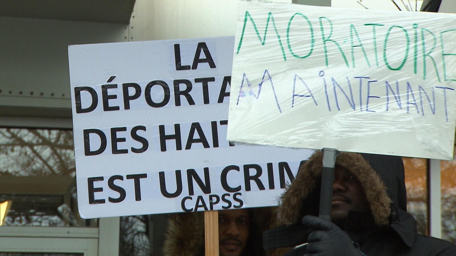 Des manifestants tiennent des pancartes.