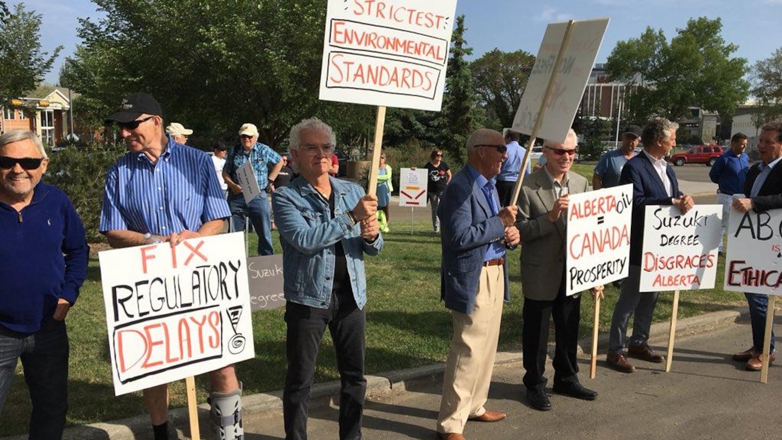 Une demi-douzaine d'hommes brandissent des pancartes avec des slogans qui supportent l'industrie pétrolière albertaine.
