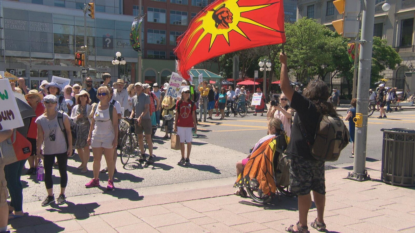 Un manifestant tient un drapeau autochtone devant un groupe de manifestants.