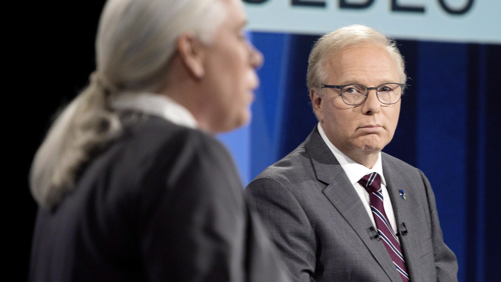 Jean-François Lisée observe Manon Massé pendant qu'elle s'exprime durant un des débats des chefs.
