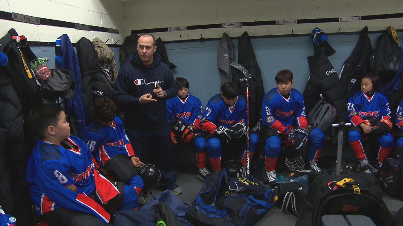 Un entraîneur parle aux hockeyeurs dans la chambre des joueurs.