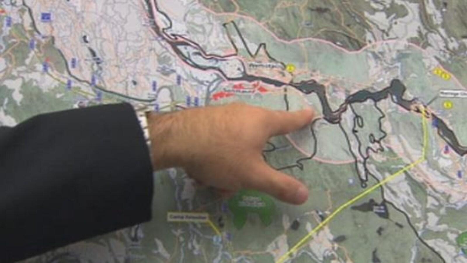 Une main pointe une rivière sur une carte.