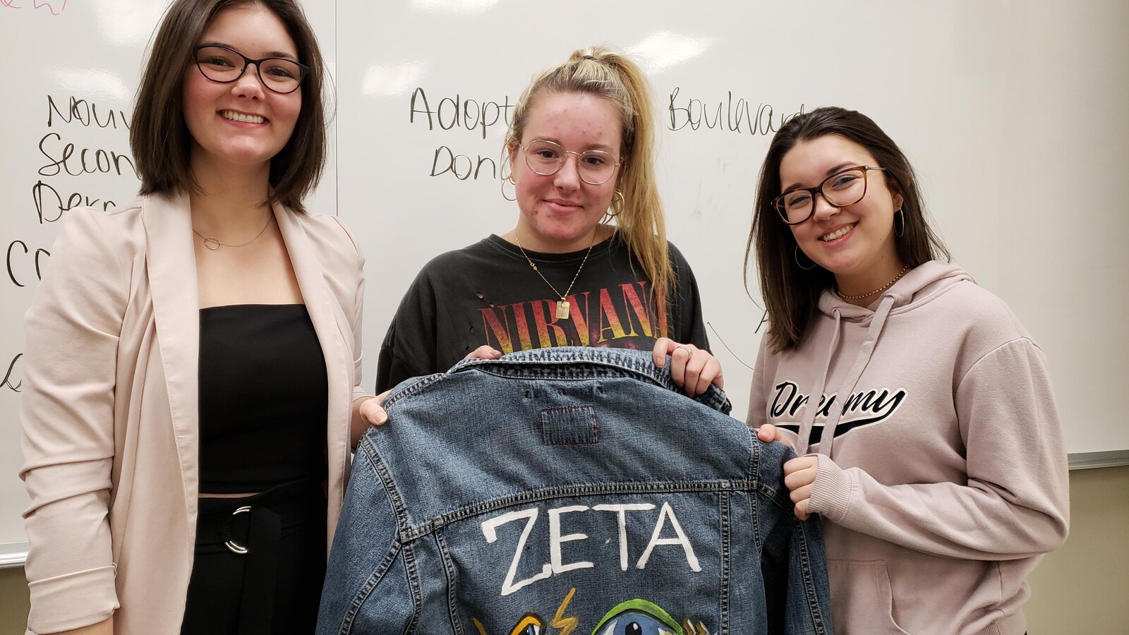 Trois jeunes femmes montrent une veste.