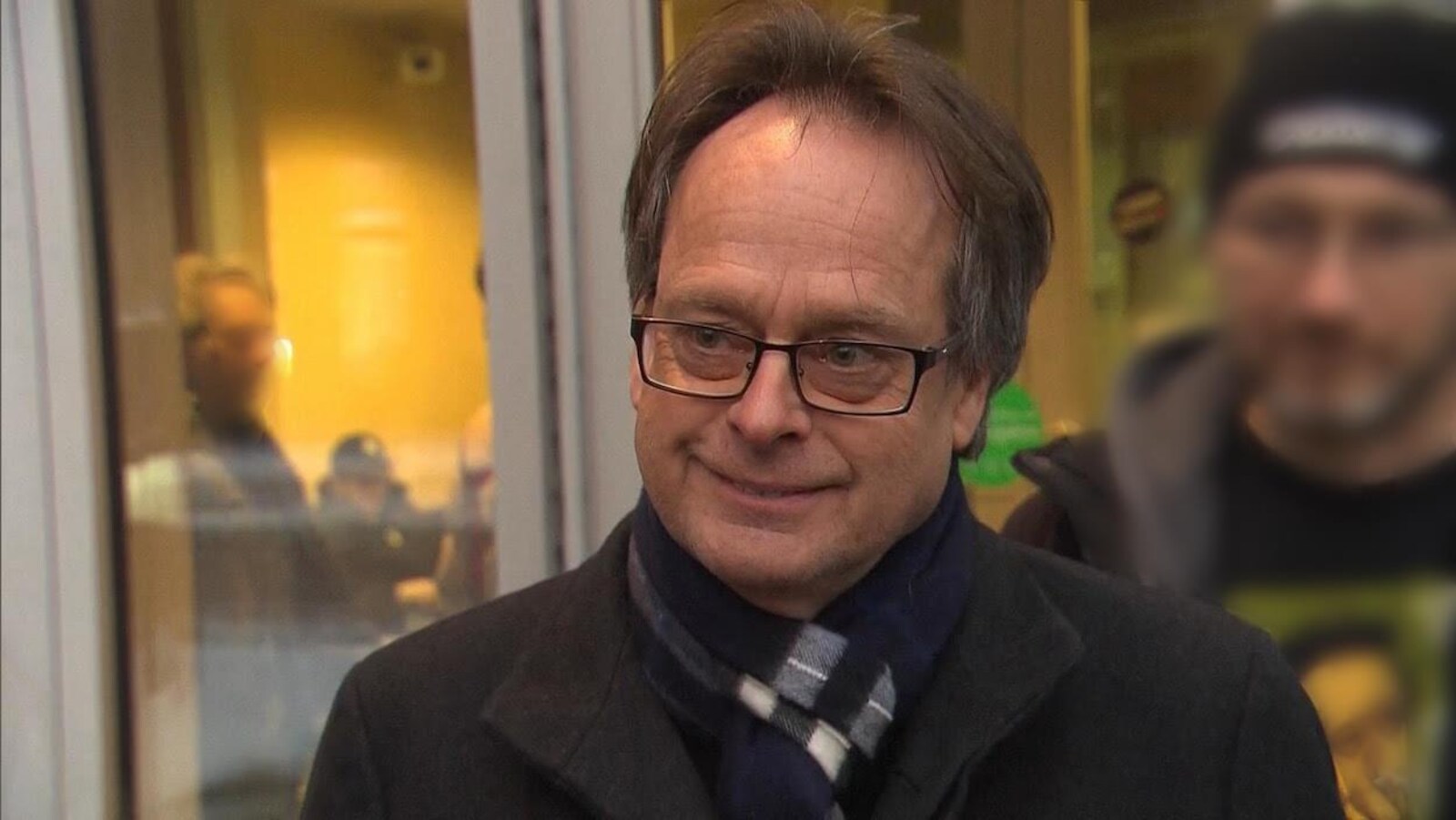 Marc Emery sourit, des gens indistincts sont en arrière-plan.
