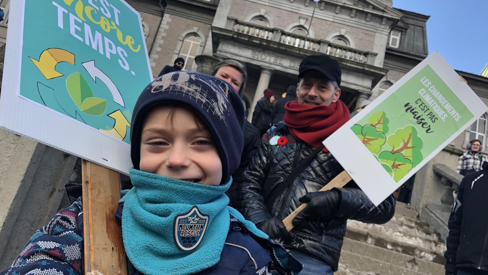 Un enfant et un homme tiennent des pancartes.