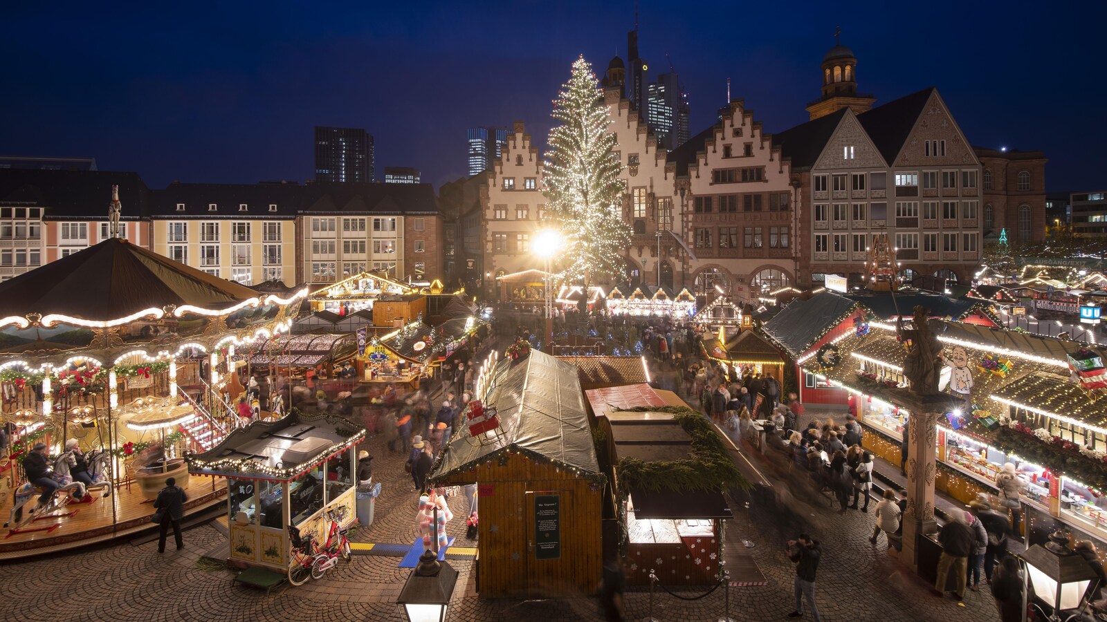 Plan panoramique du marché, avec ses stands, ses manèges et ses lumières.