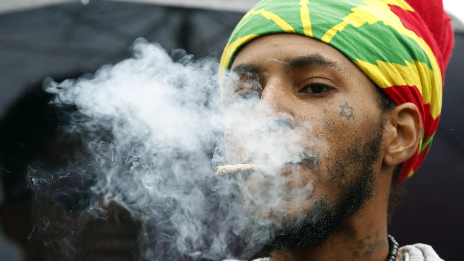 Un jeune homme fume un joint.