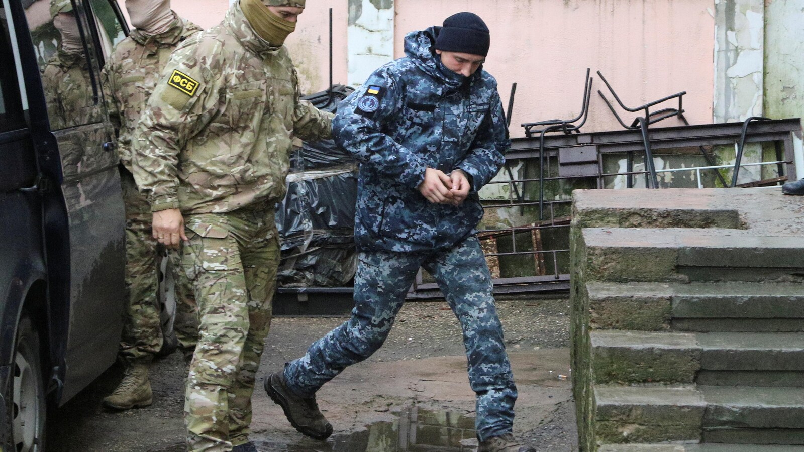 Un policier escorte un soldat menotté.