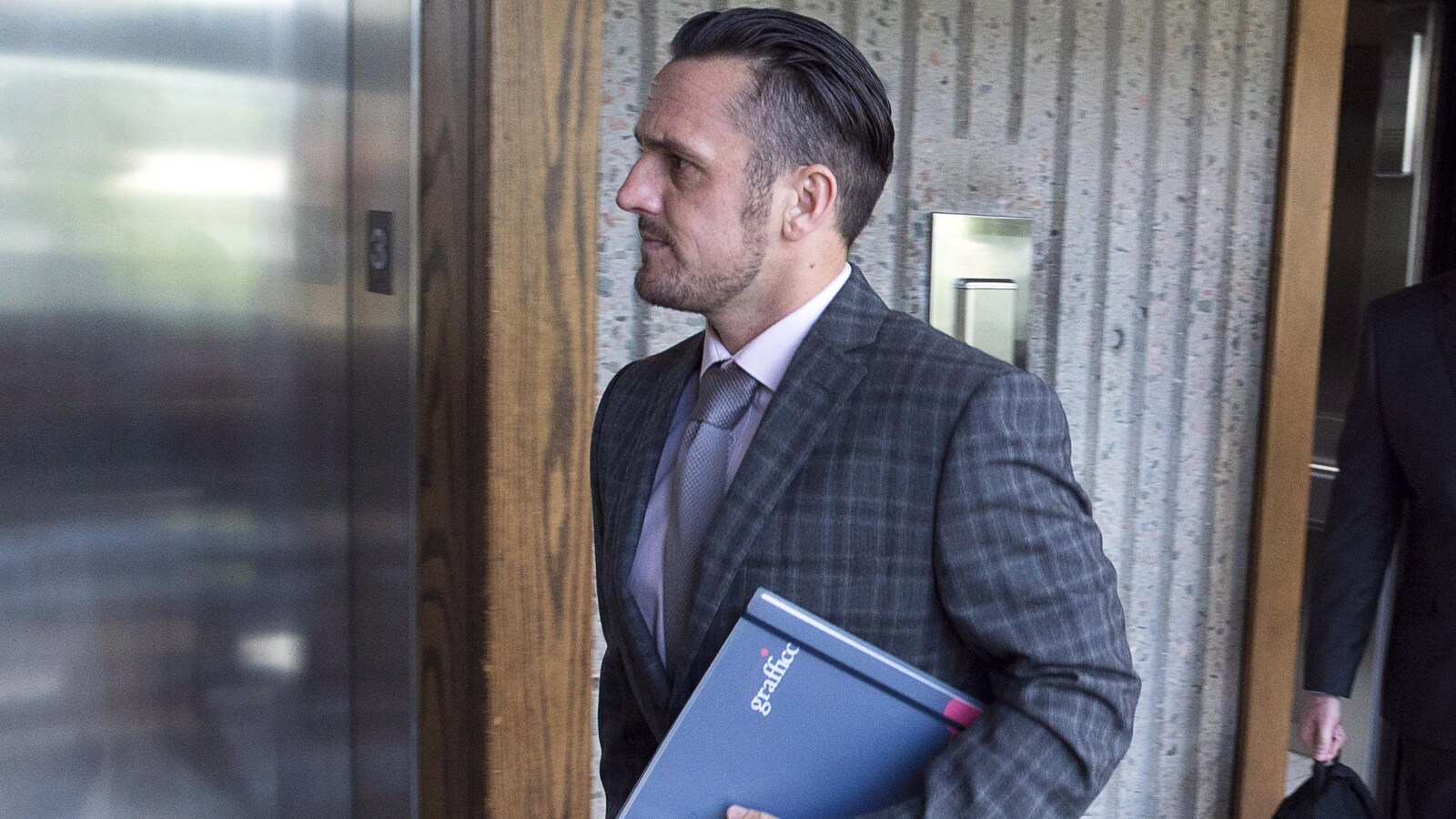 Simon Radford devant un ascenseur.
