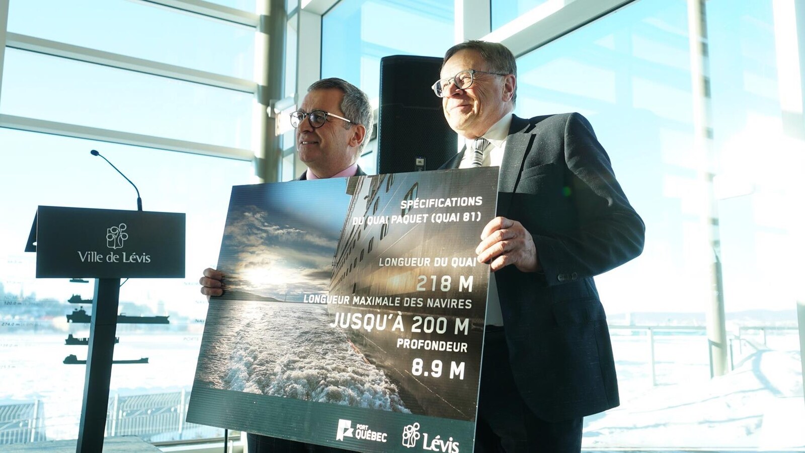 Mario Girard et Gilles Lehouillier, lors de la conférence de presse, tiennent une affiche présentant des informations sur le Quai Paquet