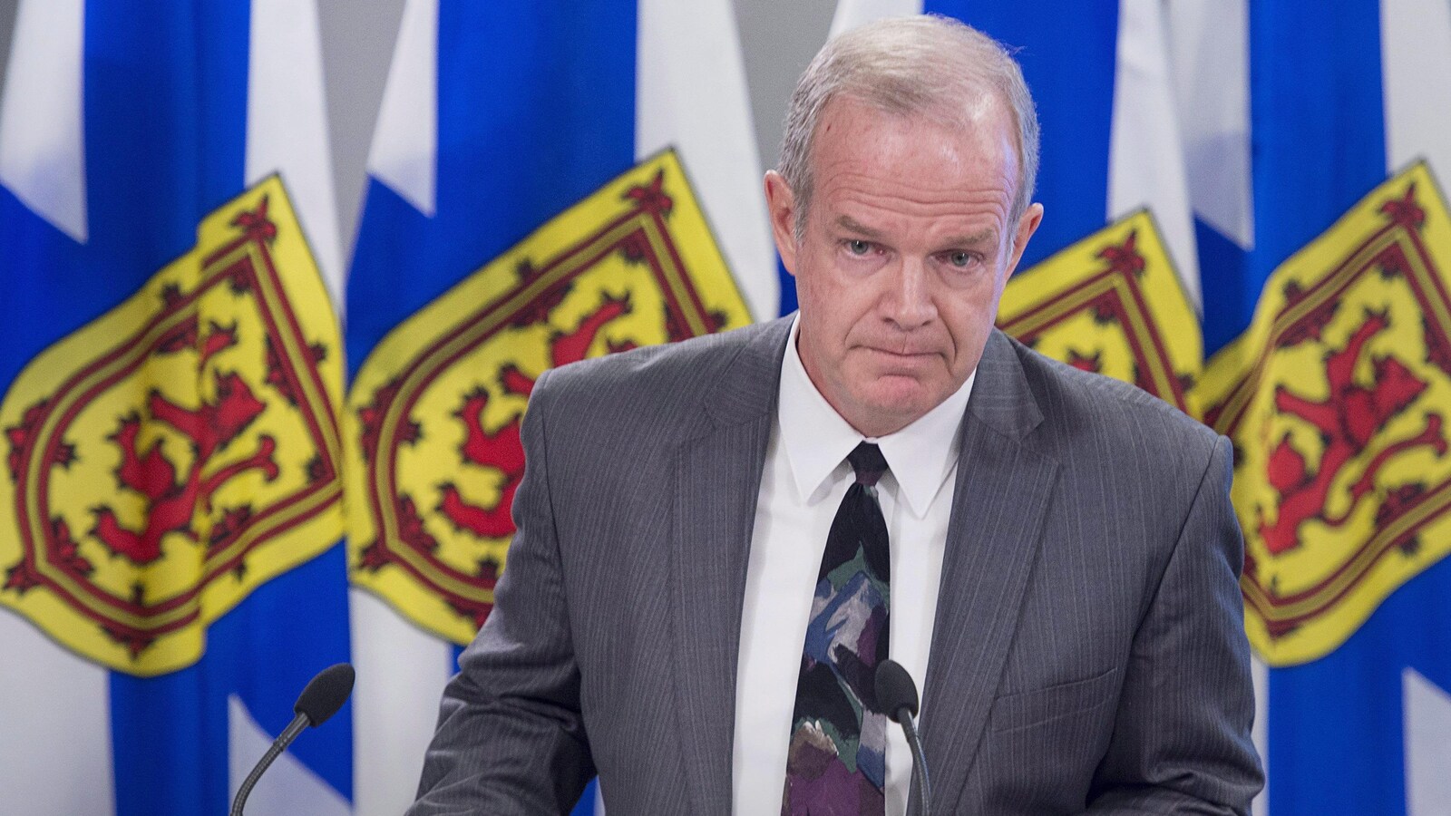 Mark Furey devant des drapeaux de la Nouvelle-Écosse.