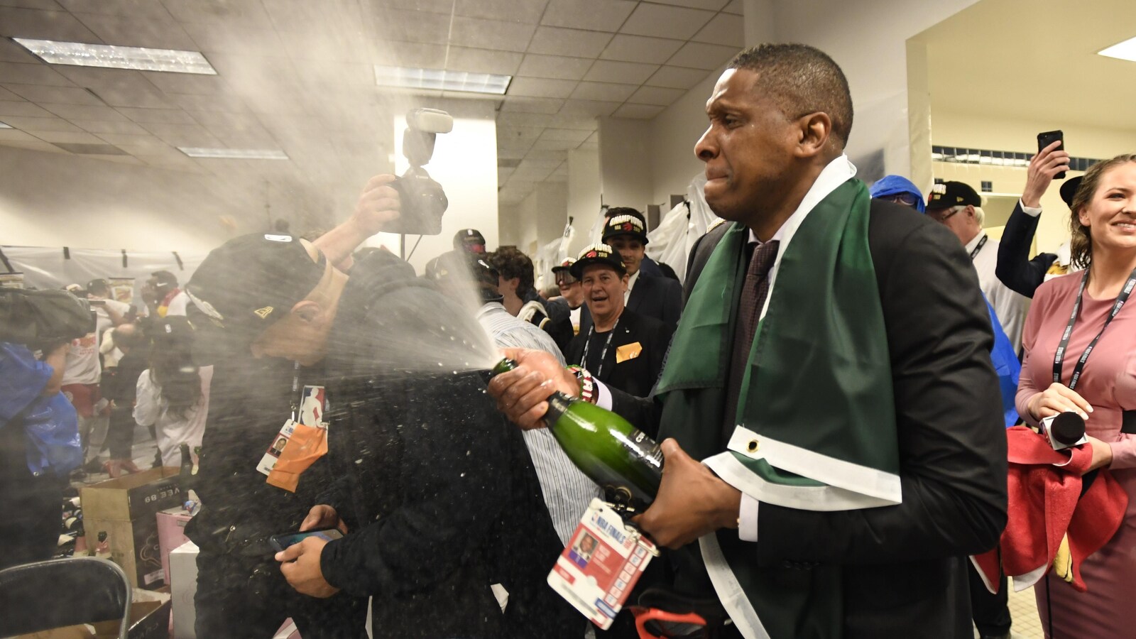 Photo d'un homme qui fait couler une bouteille de champagne dans un vestiaire.