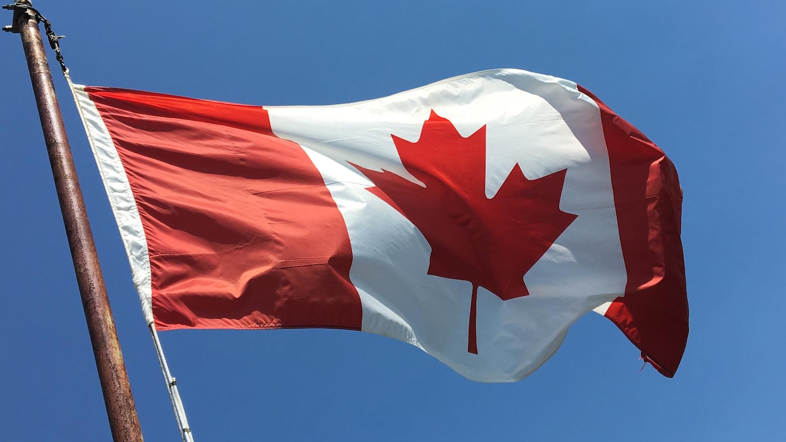 Un drapeau du Canada flottant dans le vent, attaché sur un mât.