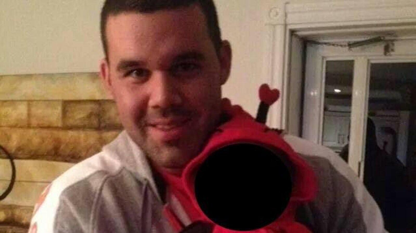 L'homme de forte stature fait la pose avec un enfant dans les bras