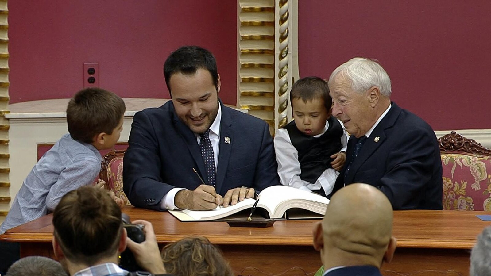 Mathieu Lacombe qui signe un livre, entouré de sa famille.