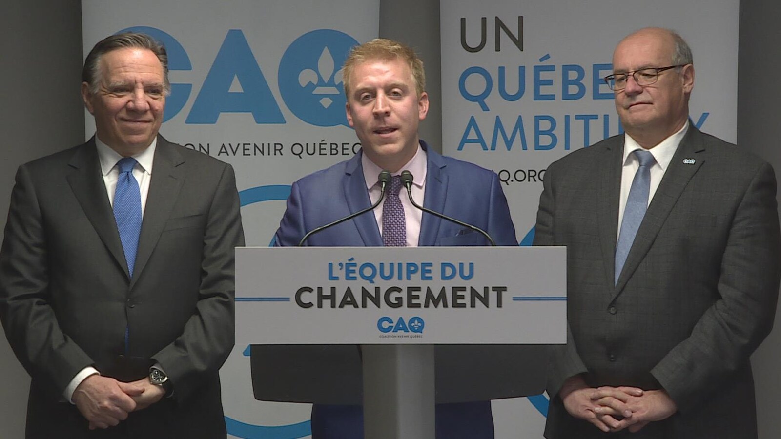 Les trois sont devant des panneaux affichant les couleurs de la CAQ.