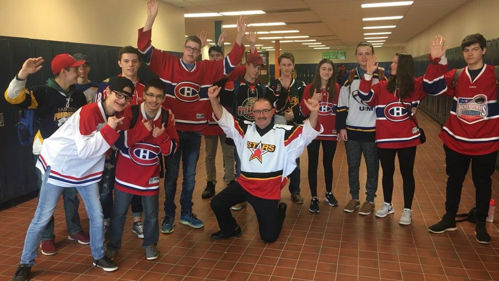 Une douzaine de jeunes autour du directeur lèvent les bras en signe de soutien.