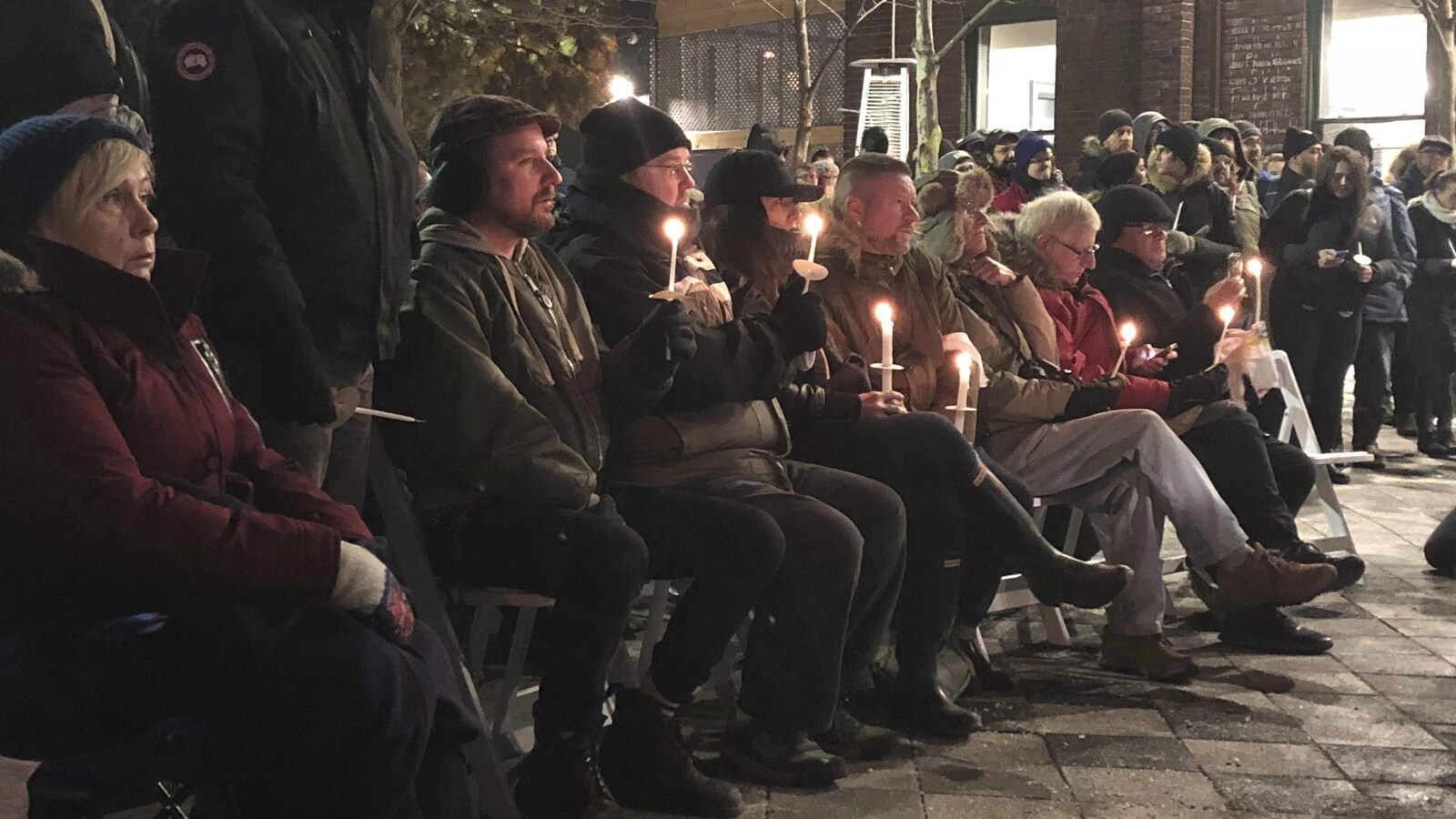 Des gens assemblés près d'une église font une veillée à la chandelle pour commémorer les victimes du présumé tueur en série Bruce McArthur.