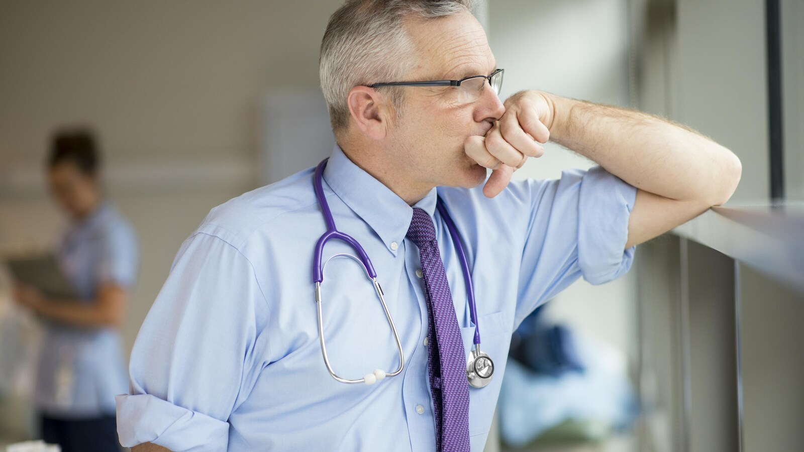 Un médecin épuisé prend une pause pour regarder dans le néant.