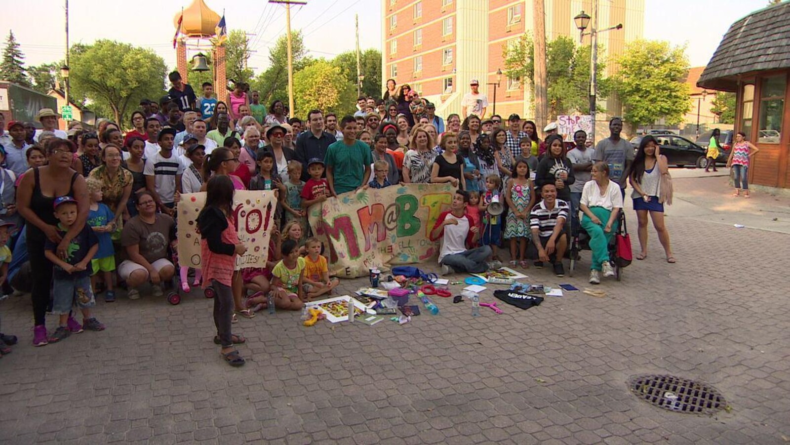 Des dizaines de personnes souriantes devant un clocher dans le North End de Winnipeg.