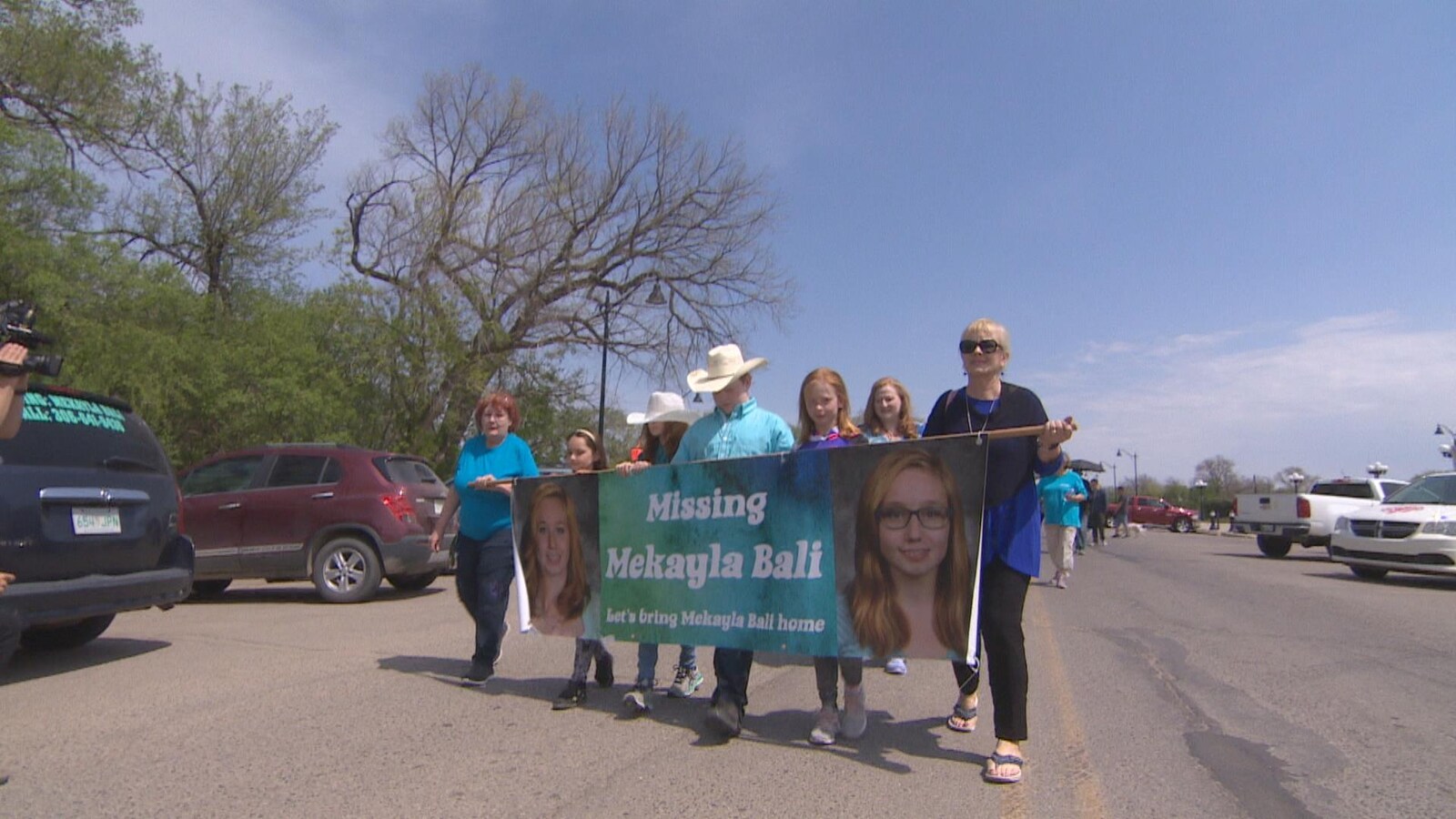 Des personnes tiennent une banderole avec le visage de Mekayla Bali pour ouvrir la marche de l'espoir