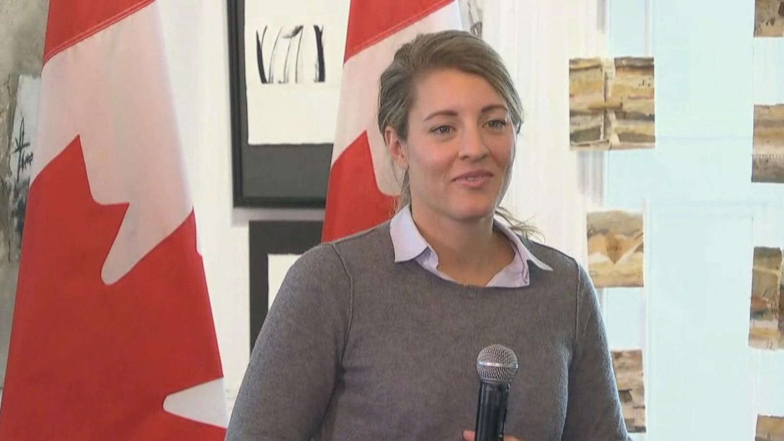 Une femme devant des drapeaux du Canada.