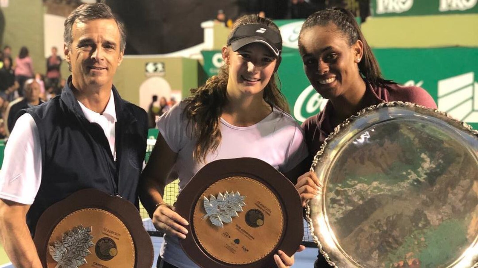 Un homme et deux jeunes femmes tiennent des trophées ronds