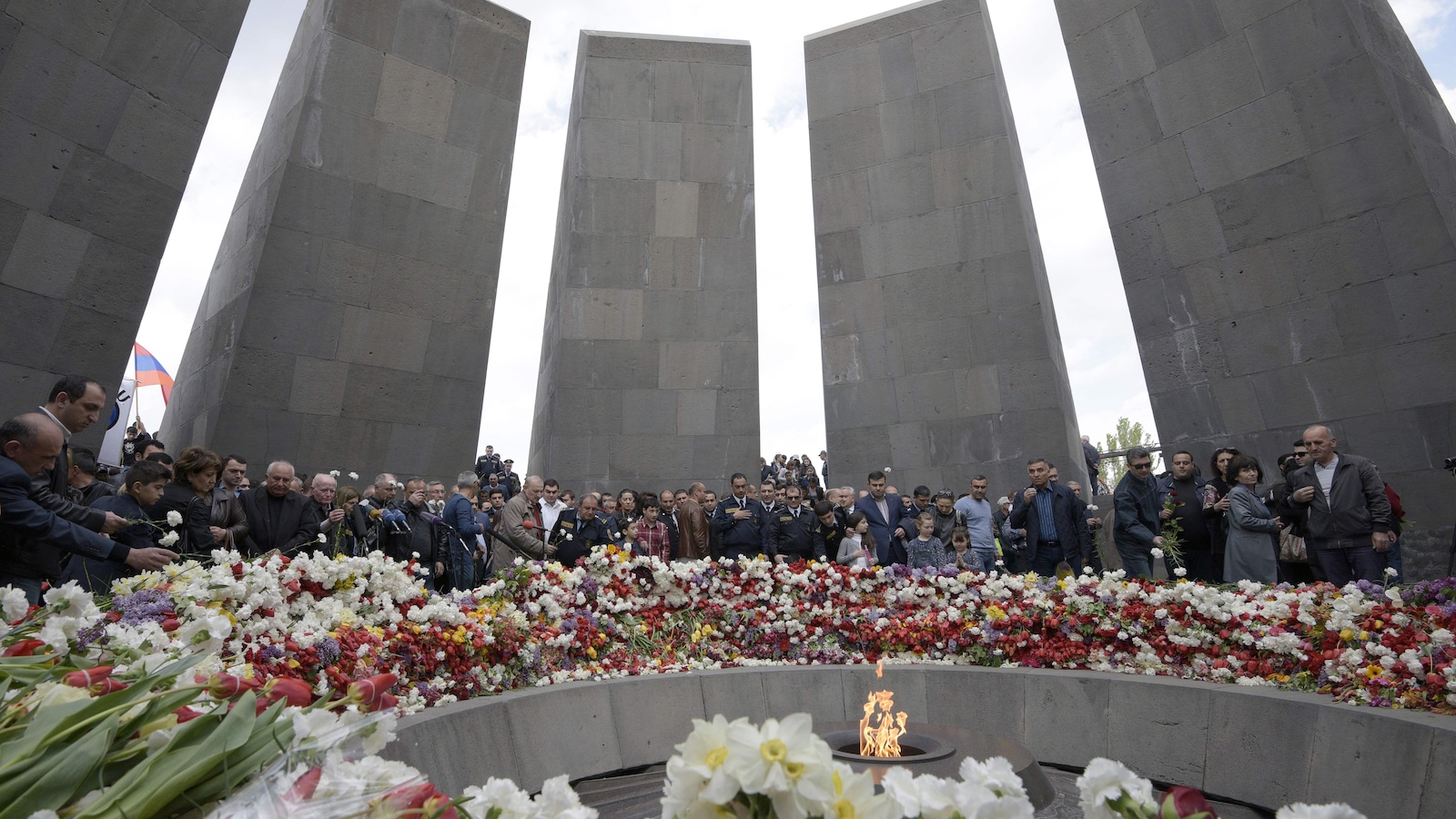 Plusieurs personnes réunies dans le mémorial rempli de fleurs
