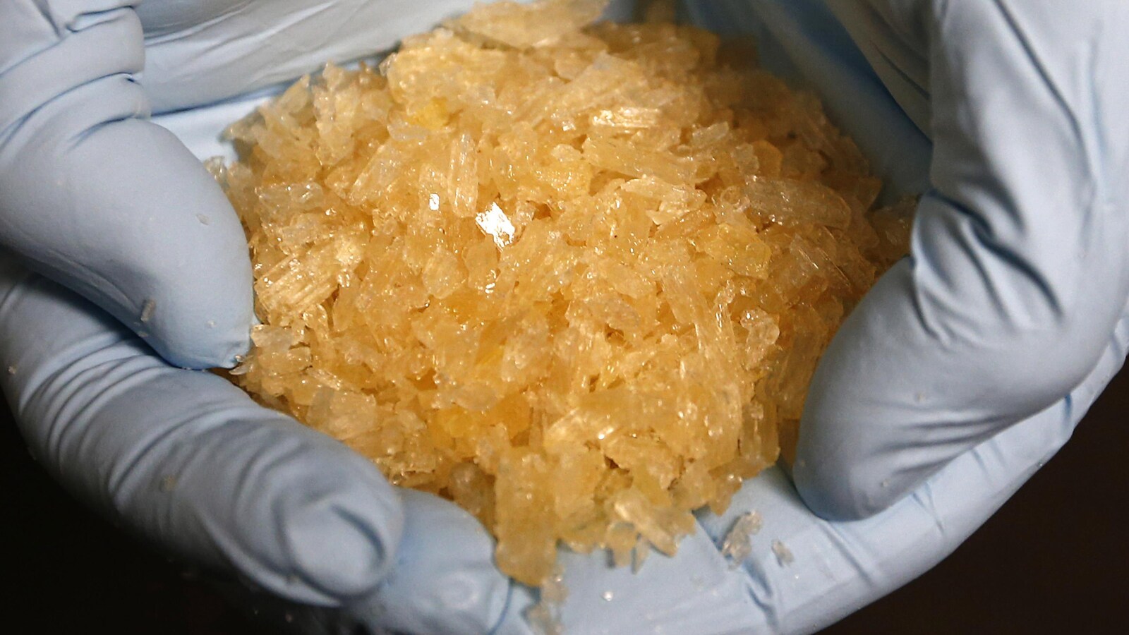 Des cristaux de méthamphétamine dans une main gantée.