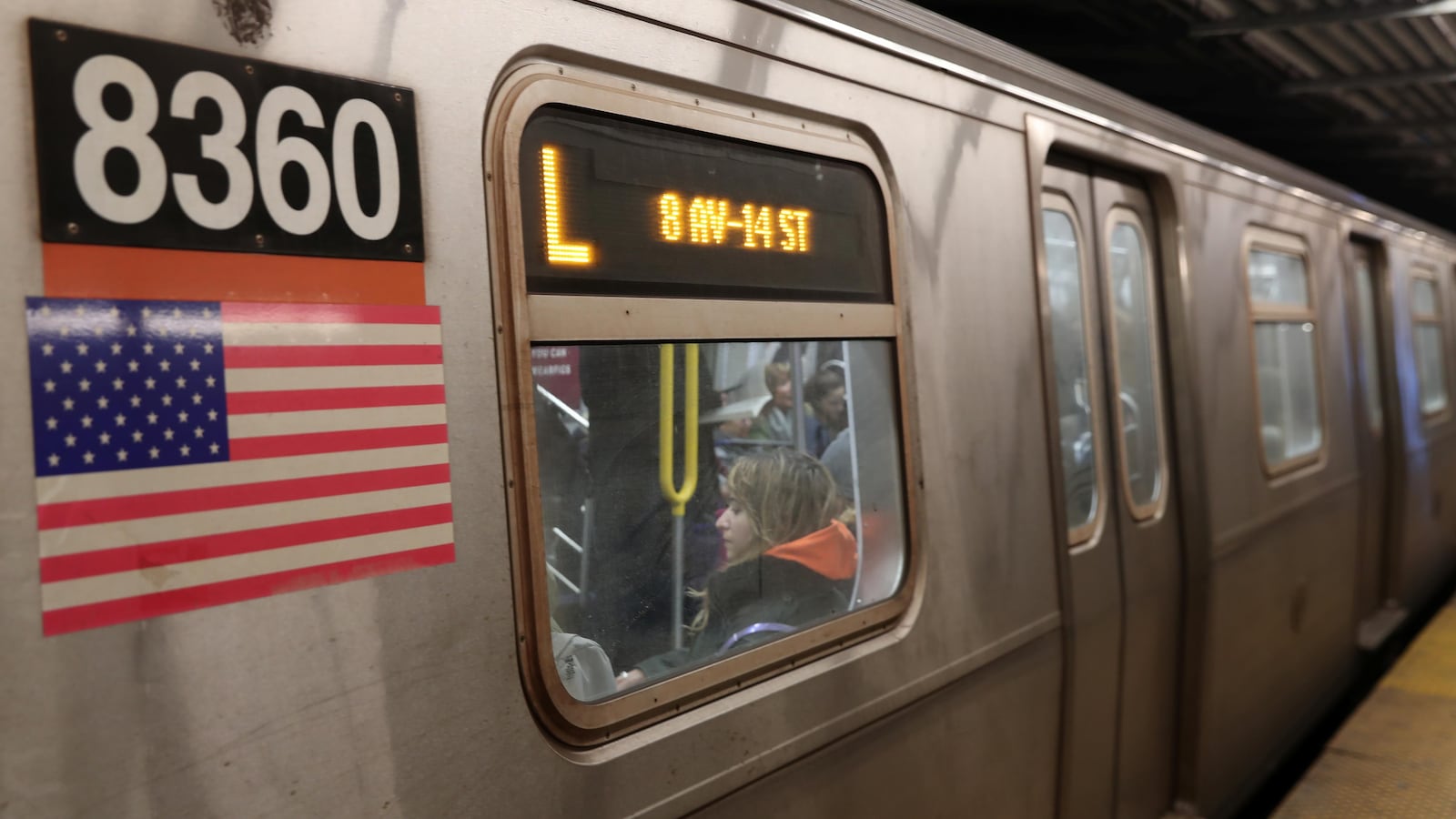 Une voiture du métro new-yorkais affiche le chiffre 8360, surplombant un drapeau américain. Il est d'un gris métallique.