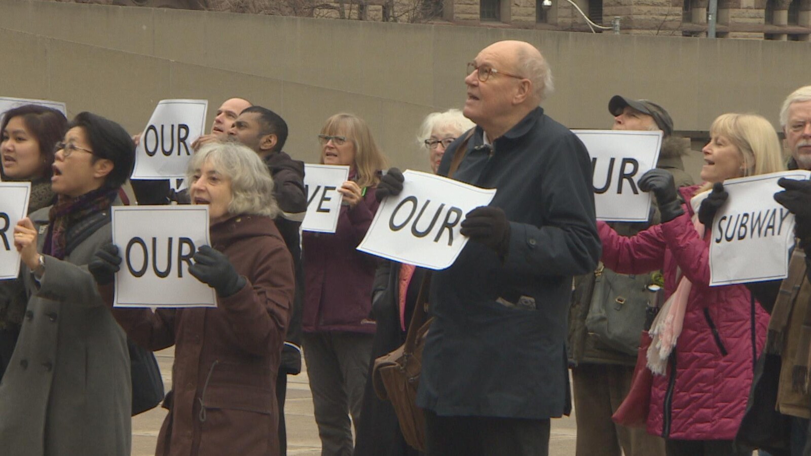 Avant la réunion du comité exécutif , une quinzaine d'opposants à la prise en charge se sont réunis à l'extérieur de l'hôtel de ville de Toronto, avec, en main, des affiches où était écrit « Sauvez notre métro ». on voit des opposants brandir ces affiches